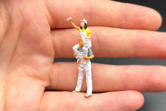 Hand-painted 1:64 scale painter figures standing on the palm of a hand, showing how small they are